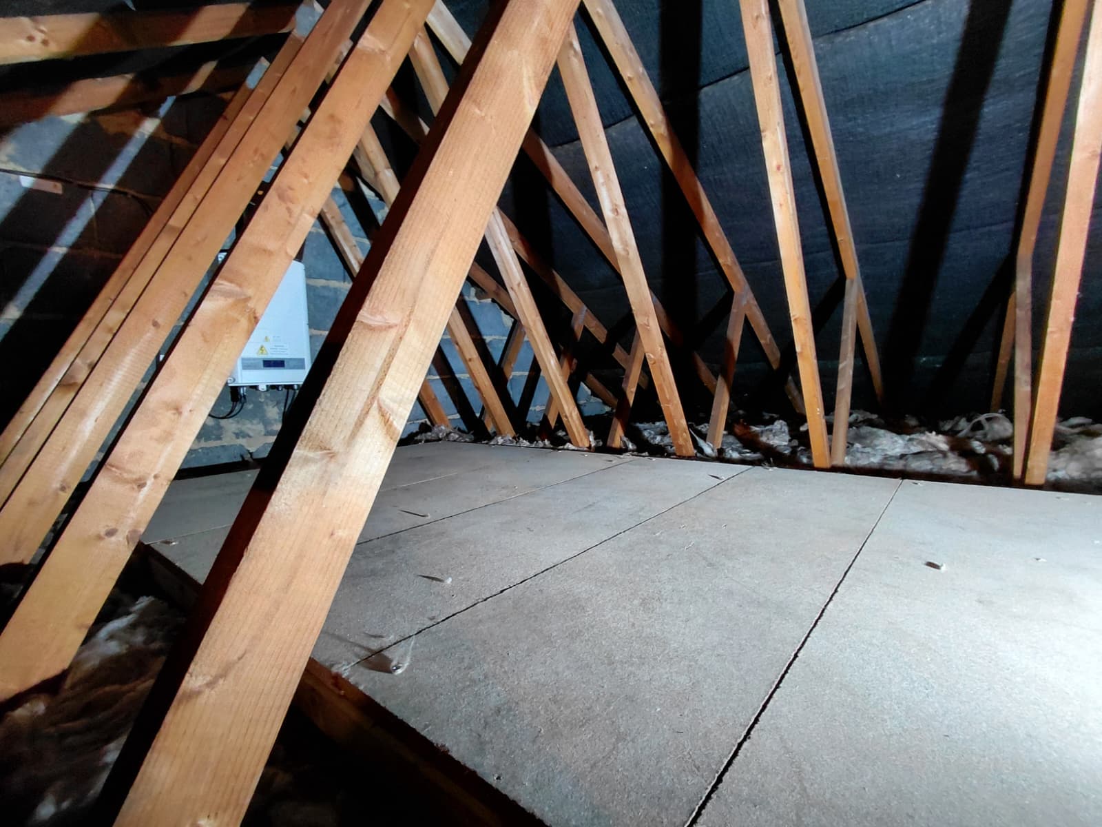 Raised loft boarding run across trussed rafters with mineral wool beneath
